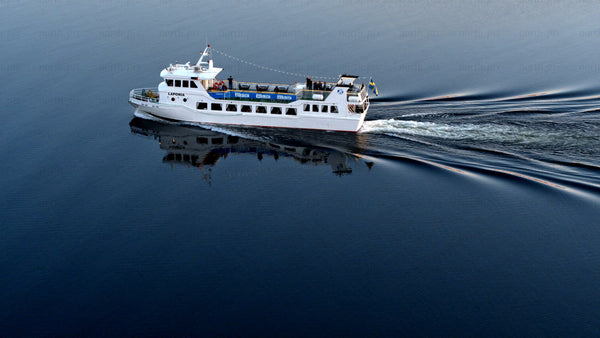 White passenger ferry sails on the Luleälven in Luleå on a summer day
