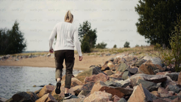 Woman walks on rocks by the water in Luleå archipelago on a summer day
