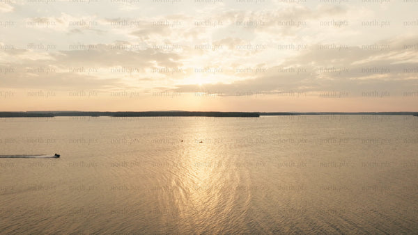 Sunset over calm lake with jet ski and kayaks in Luleå