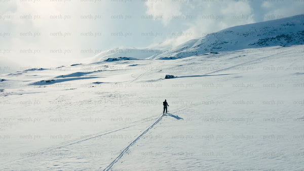 Lone skier crosses snowy expanse in mountainous winter landscape