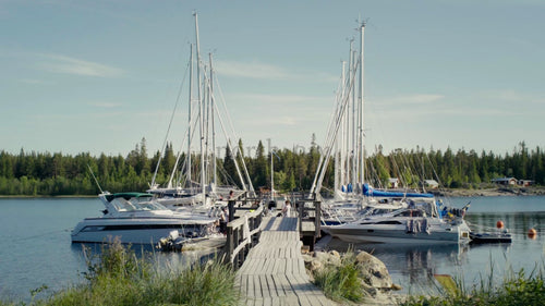 Sommardag i Kluntarnas skärgård: Segelbåtar och motorbåtar förtöjda vid träbrygga, Luleå, Sverige