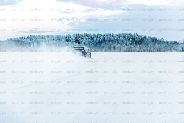 Car driving on snow-covered field in winter daytime