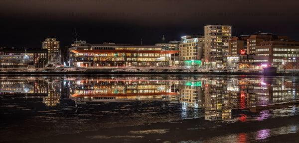 Riverfront buildings reflected on icy water at night
