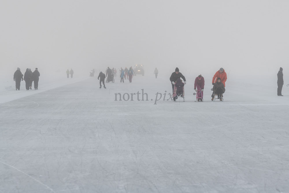 People skating and pushing sleds on frozen lake, winter