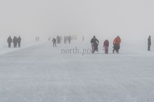 People skating and pushing sleds on frozen lake, winter