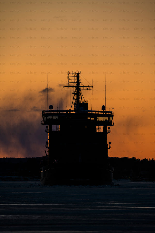 Icebreaker ship silhouette at sunset over ice