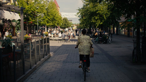 Kvinna på cykel i Luleå centrum under solig sommardag