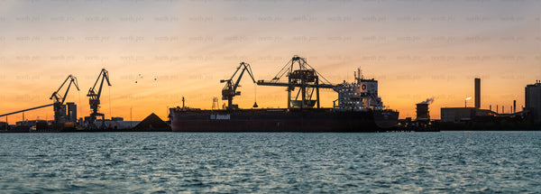 Cargo ship and loading cranes at sunset port