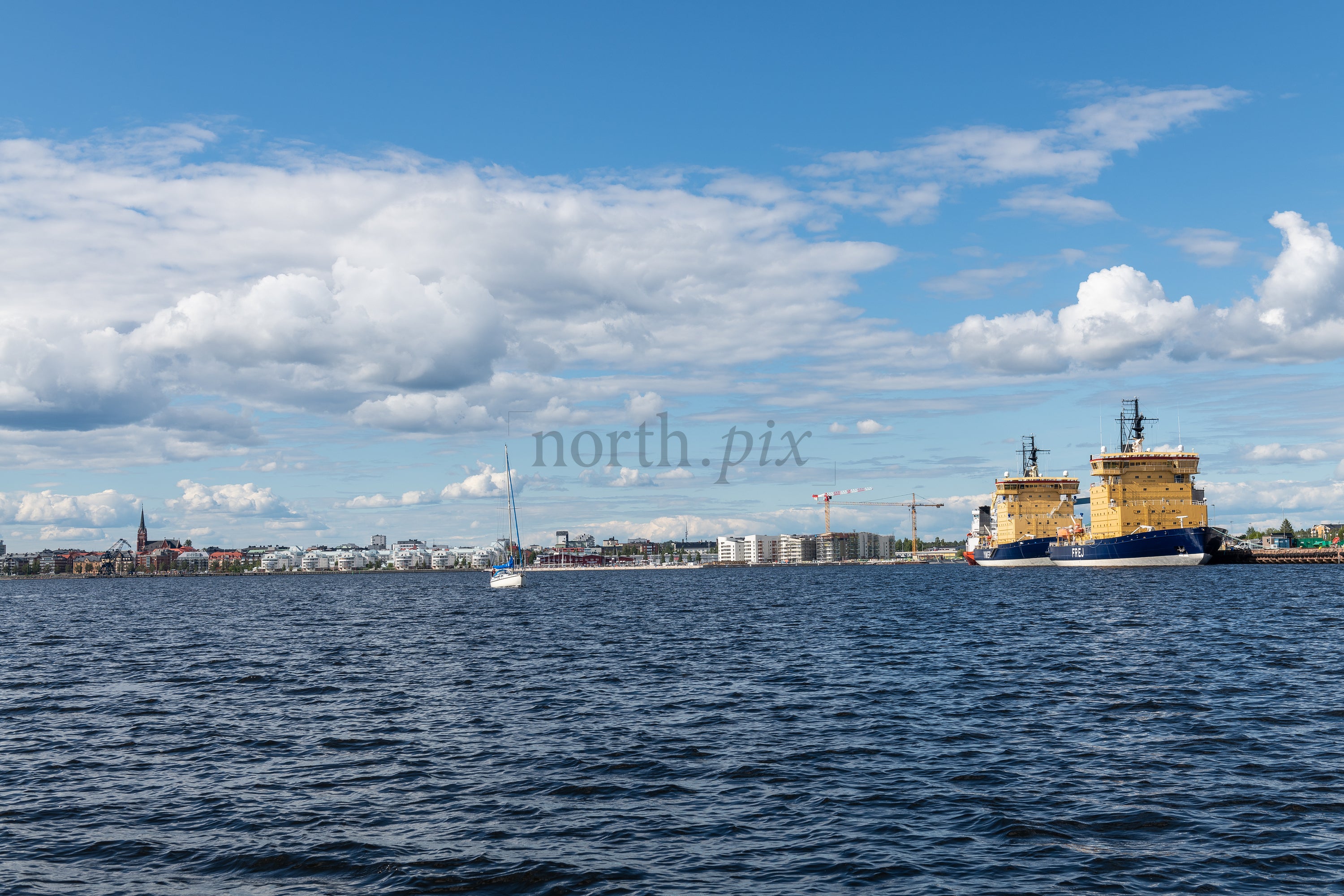 Cargo ships docked at coastal harbor under blue sky