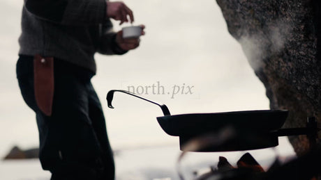 Man Cooking on Open Fire on Winter Beach in Lulea Archipelago, Sweden