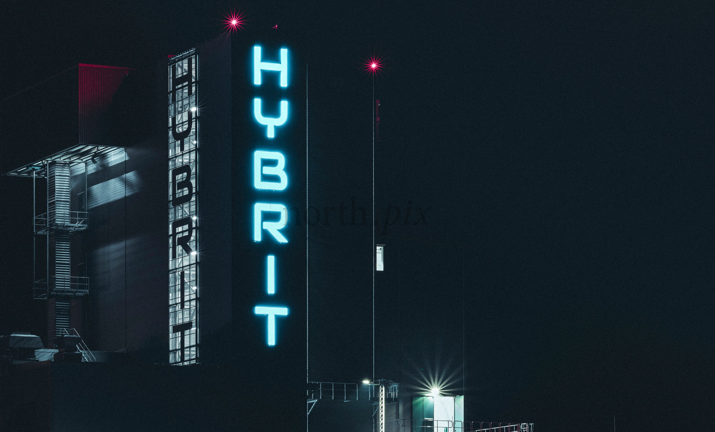 Hybrit neon sign on industrial building at night