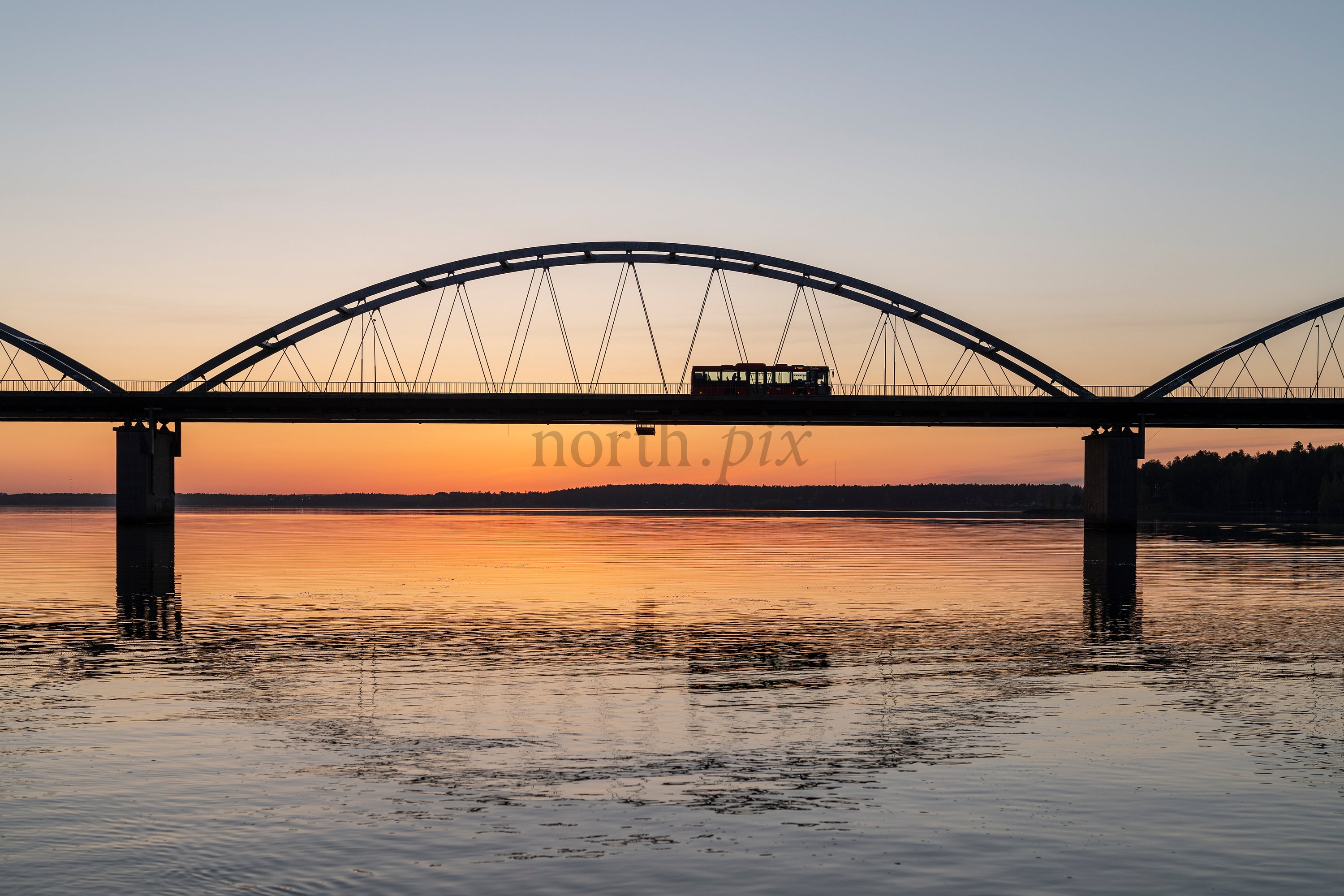Bridge with bus crossing at sunset over river