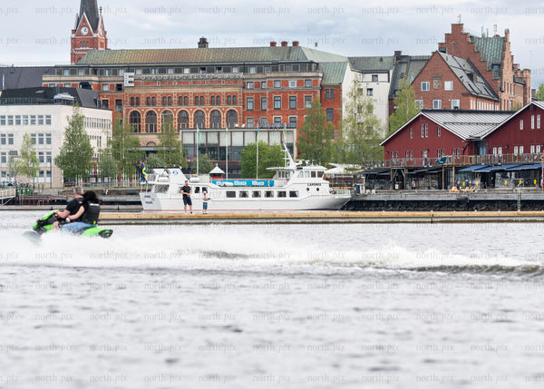 Jet ski passing passenger boat along Luleå waterfront, summer