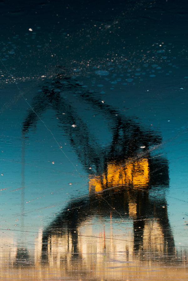 Harbor crane reflected on wet surface at dusk