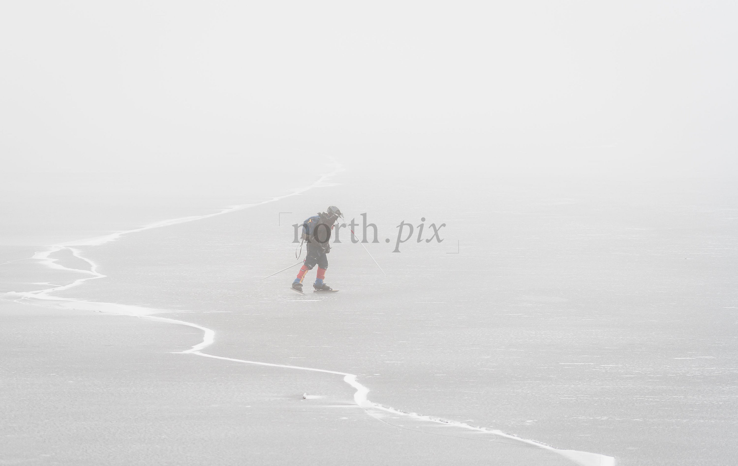 Skier crossing frozen lake in fog on winter day