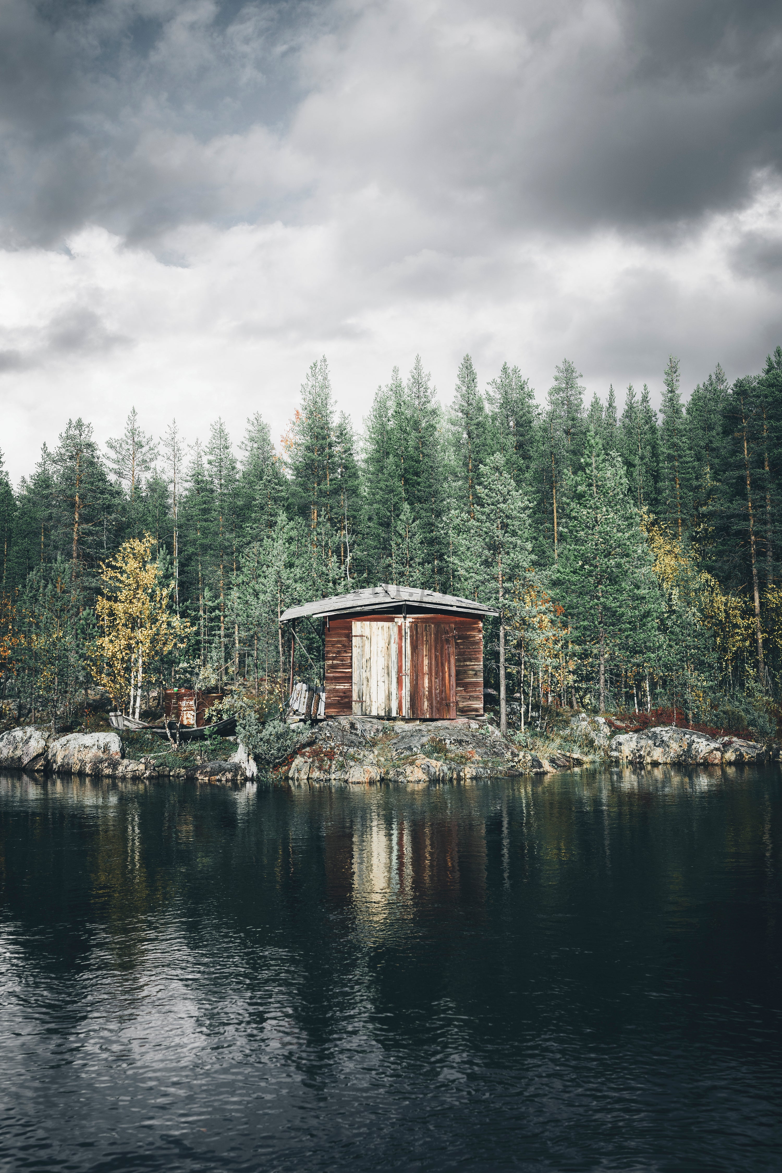 Wooden boathouse on a rocky lakeshore with pines