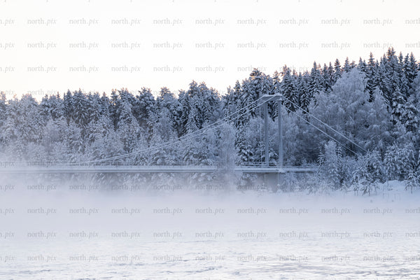 Suspension bridge crossing a river in snowy forest