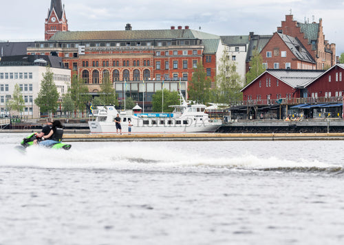 Jet ski passing passenger boat along Luleå waterfront, summer