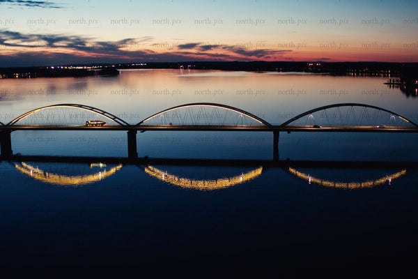 Sunset over modern arch bridges in Luleå city center with reflective calm water