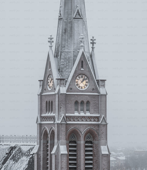 Church clock tower covered in snow on winter morning