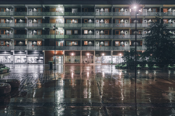 Apartment building facade at night with wet pavement