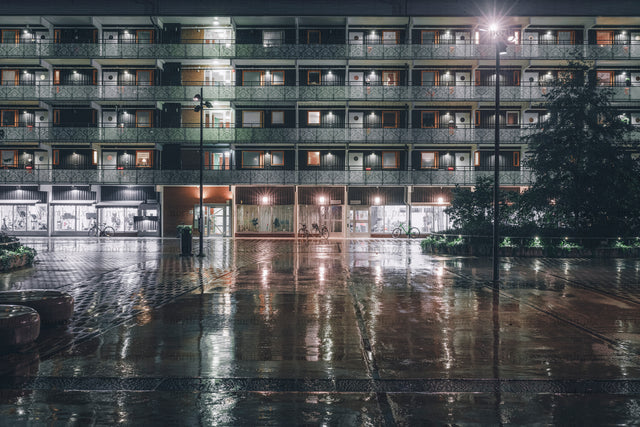 Apartment building facade at night with wet pavement
