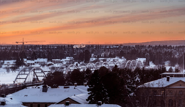 Arched bridge over snowy town at sunset