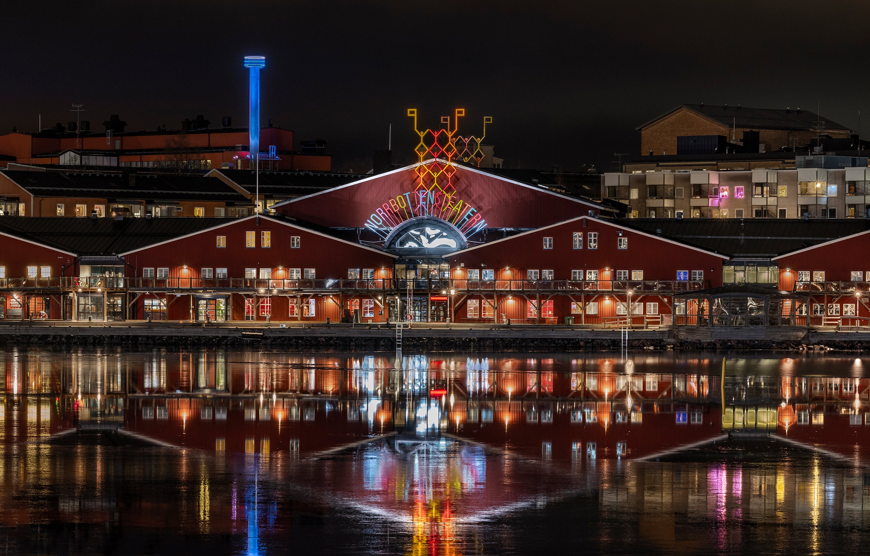 Night view of red waterfront theater with reflections