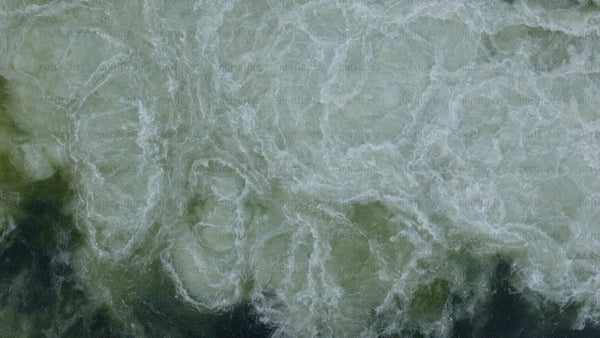 Aerial view of hydro power station dam releasing water in winter