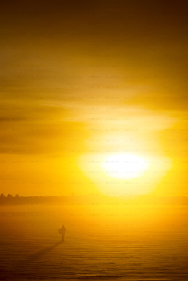 Man silhouette walking on frozen lake at sunrise