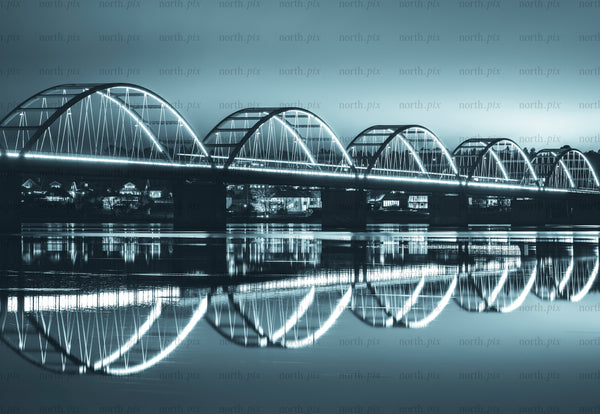 Illuminated arched bridge with reflection over river at night
