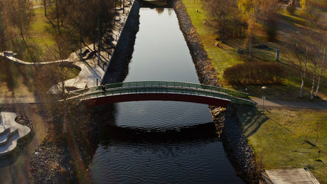 Autumn Day in Piteå City: Person Walks Over a Canal Bridge with Golden Sunlight