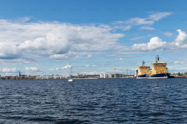 Cargo ships docked at coastal harbor under blue sky