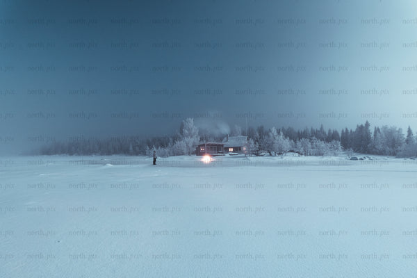 Cabin on a frozen lake at night in winter