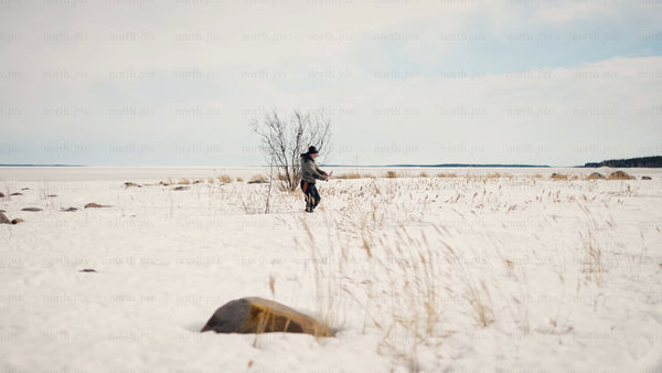 Man walking through snowy field by frozen Baltic Sea in Luleå