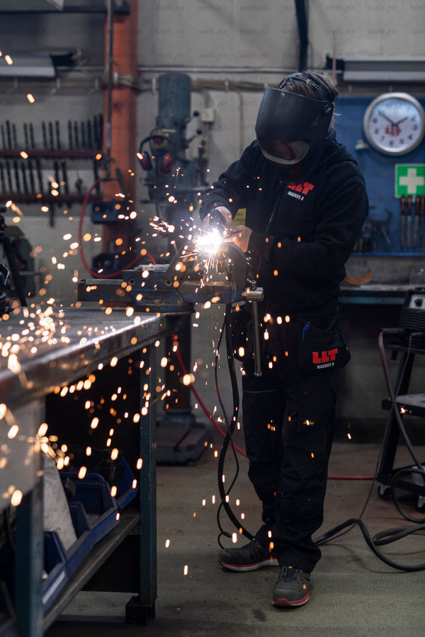 Worker welding metal in workshop with sparks
