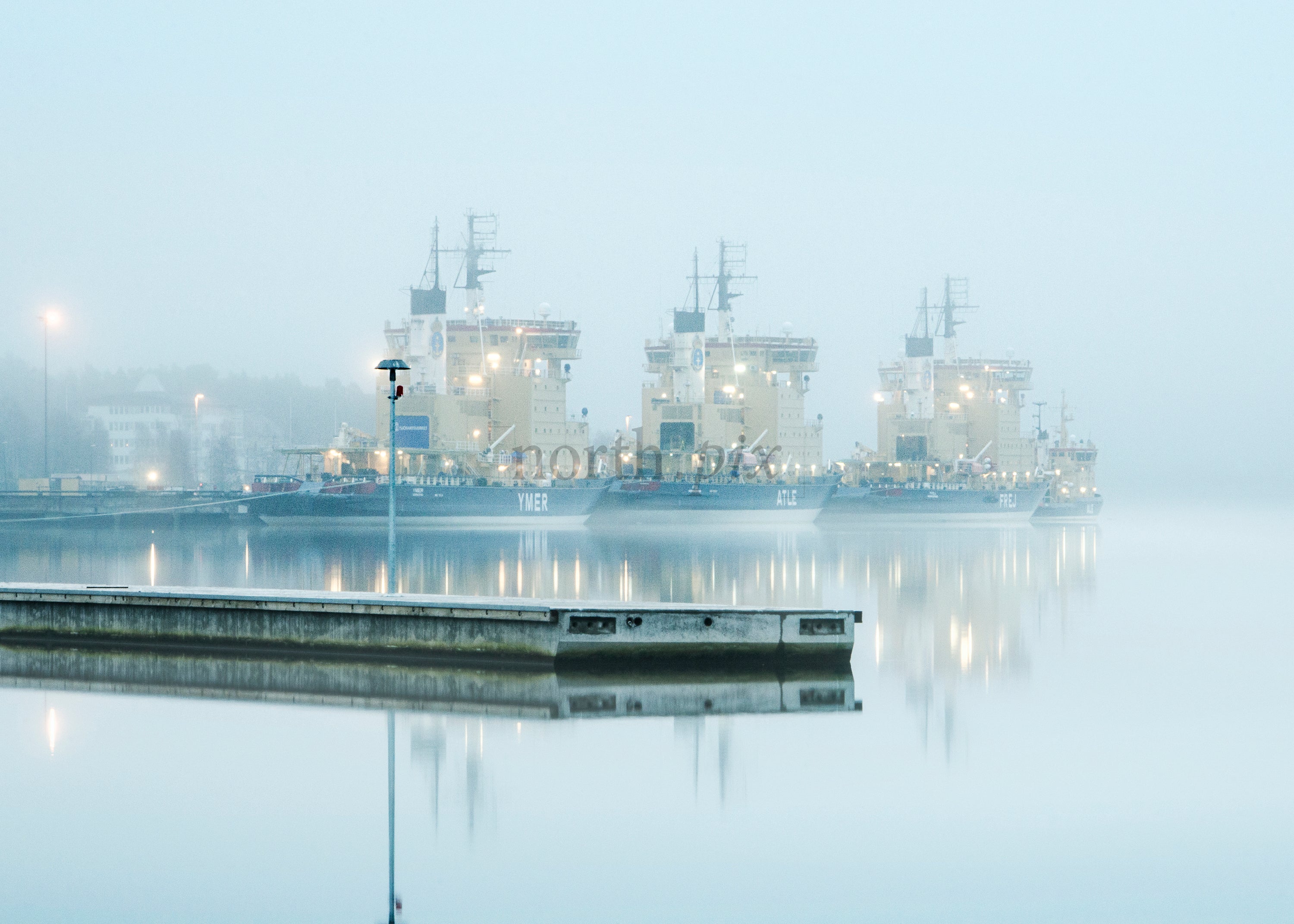 Three icebreaker ships docked in foggy harbor
