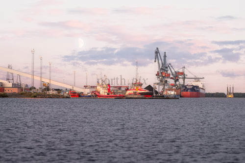 Lastfartyg och kranar i industrihamn i skymningen