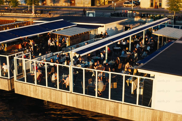 Luleå city center waterfront restaurant deck with people dining at sunset skyline