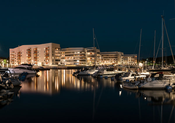 Marina with boats and lit apartment buildings at night