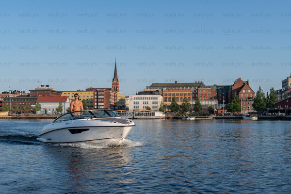 Motorboat cruising city harbor in summer morning