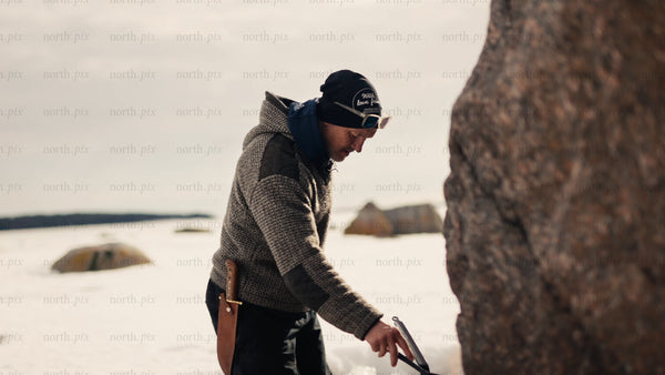 Man cooking on a portable stove by a frozen lake in Luleå archipelago winter