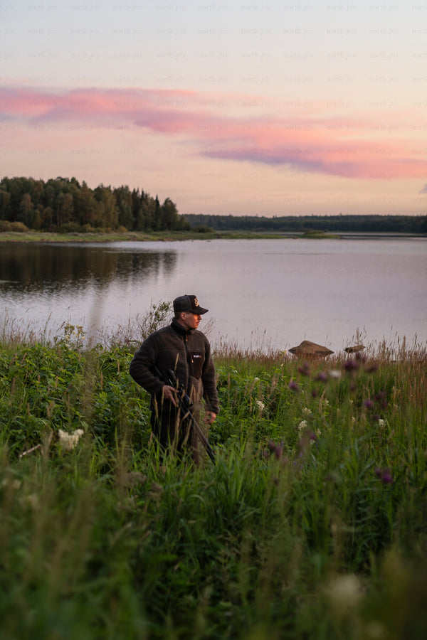 Man standing by lake at sunset in summer