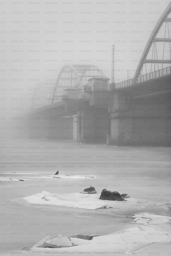 Bridge over frozen river in heavy fog