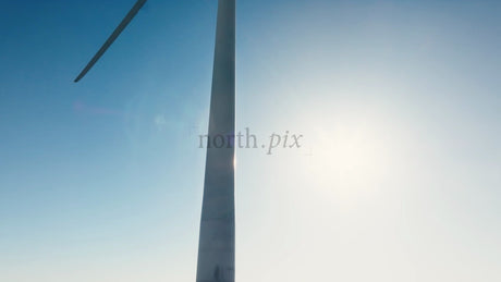 Rotating Wind Turbine Against Blue Sky and Sun: Zoom Out to Snowy Winter Landscape of Markbygden Wind Farm, Sweden