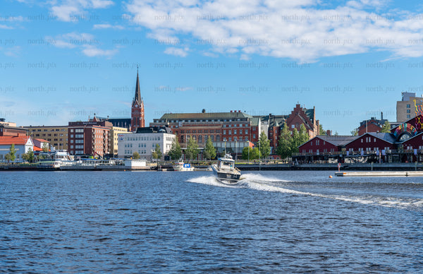 Motorboat cutting across city harbor at midday