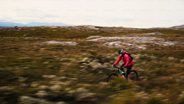Man in red jacket on mountain bike rides downhill trail