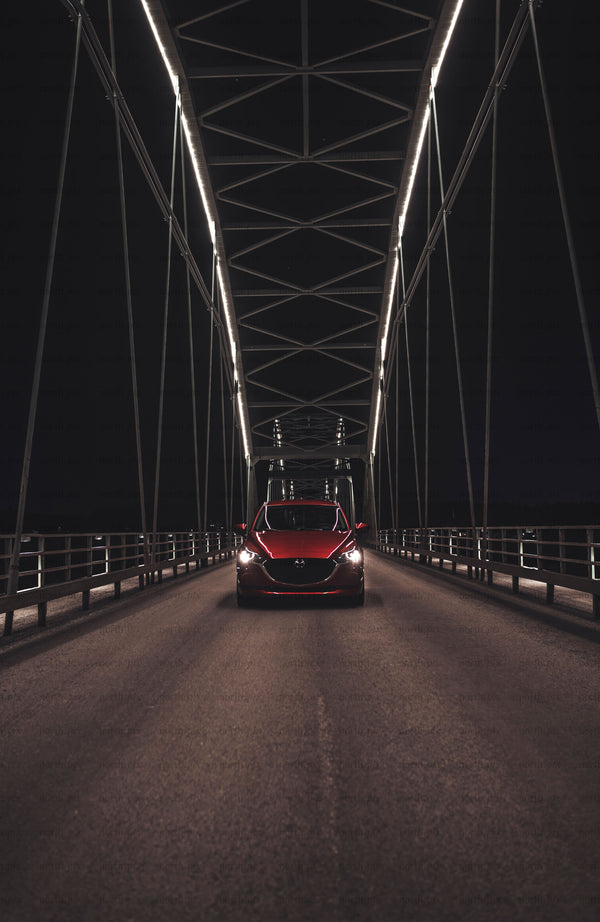 Red car on bridge at night