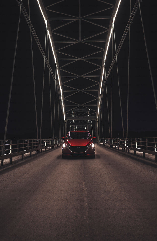 Red car on bridge at night