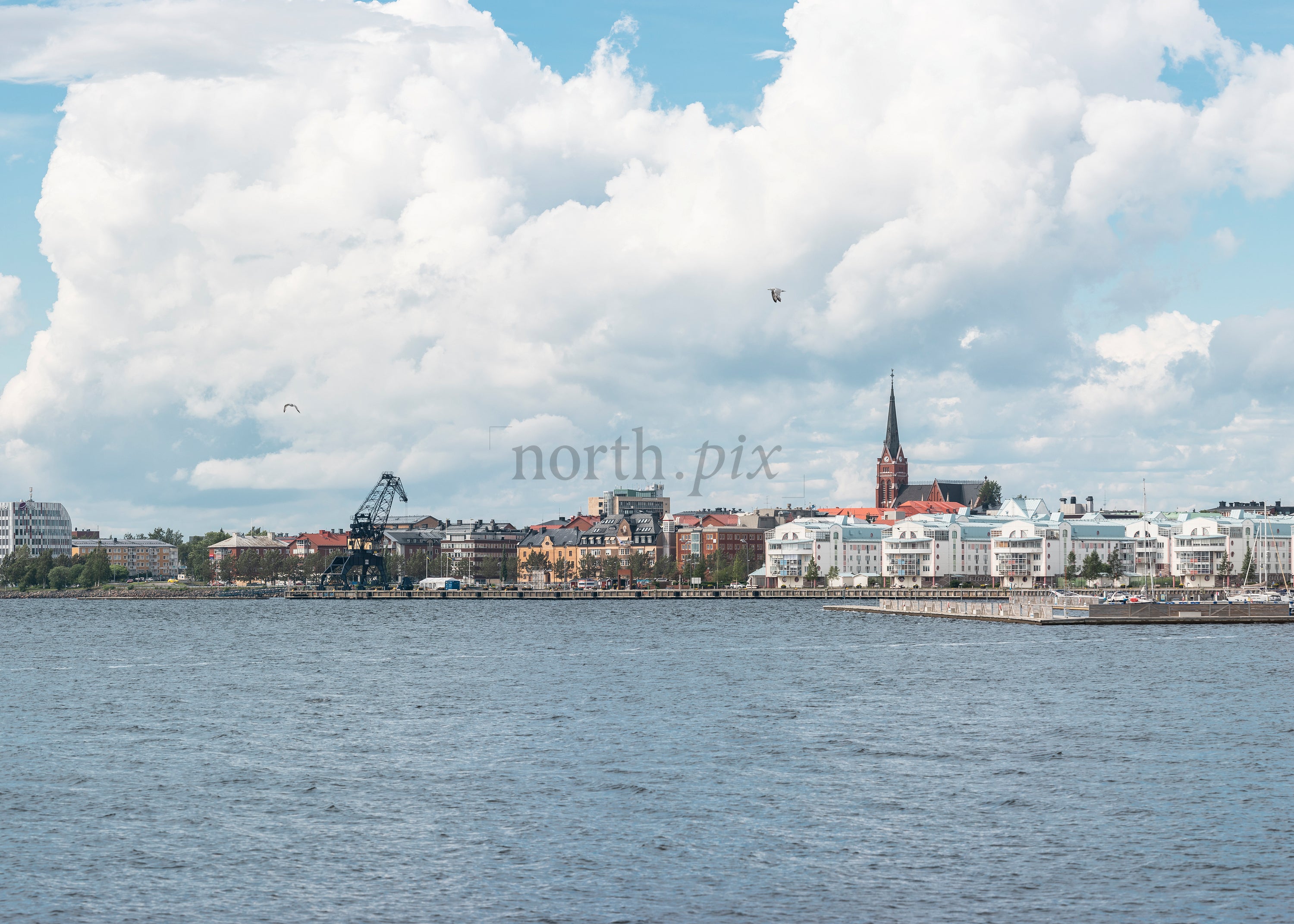 Waterfront city skyline with church spire and crane